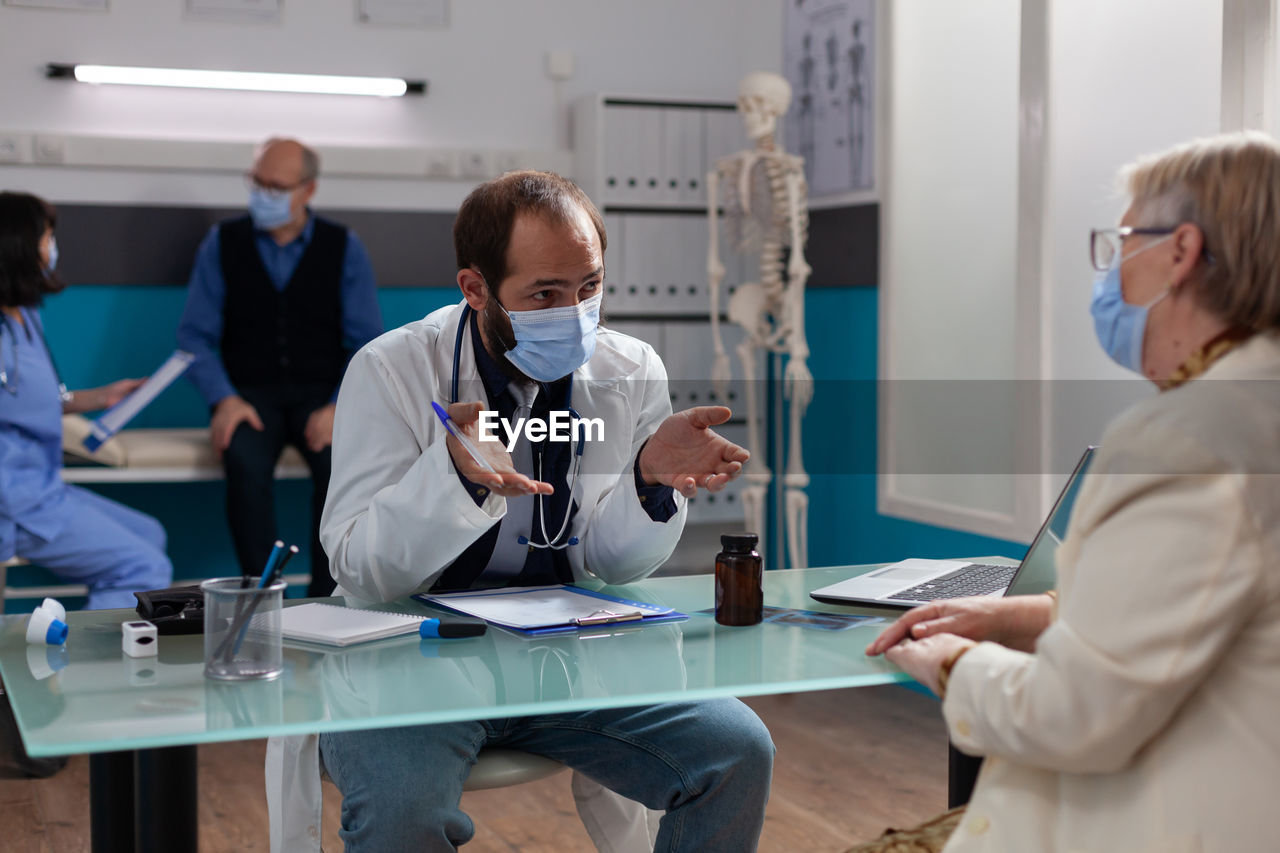 Doctor wearing mask examining patient in clinic