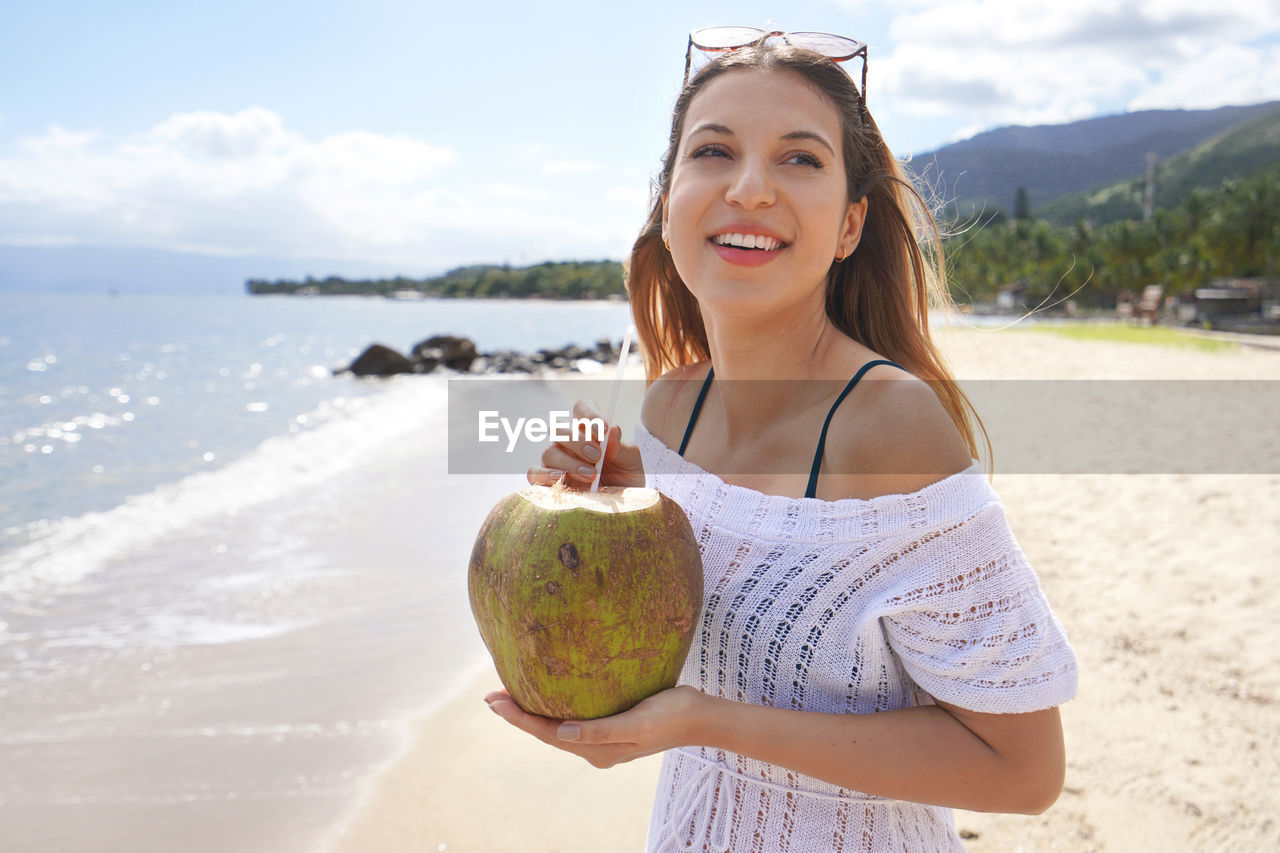 Woman drinking green coconut water on the tropical beach