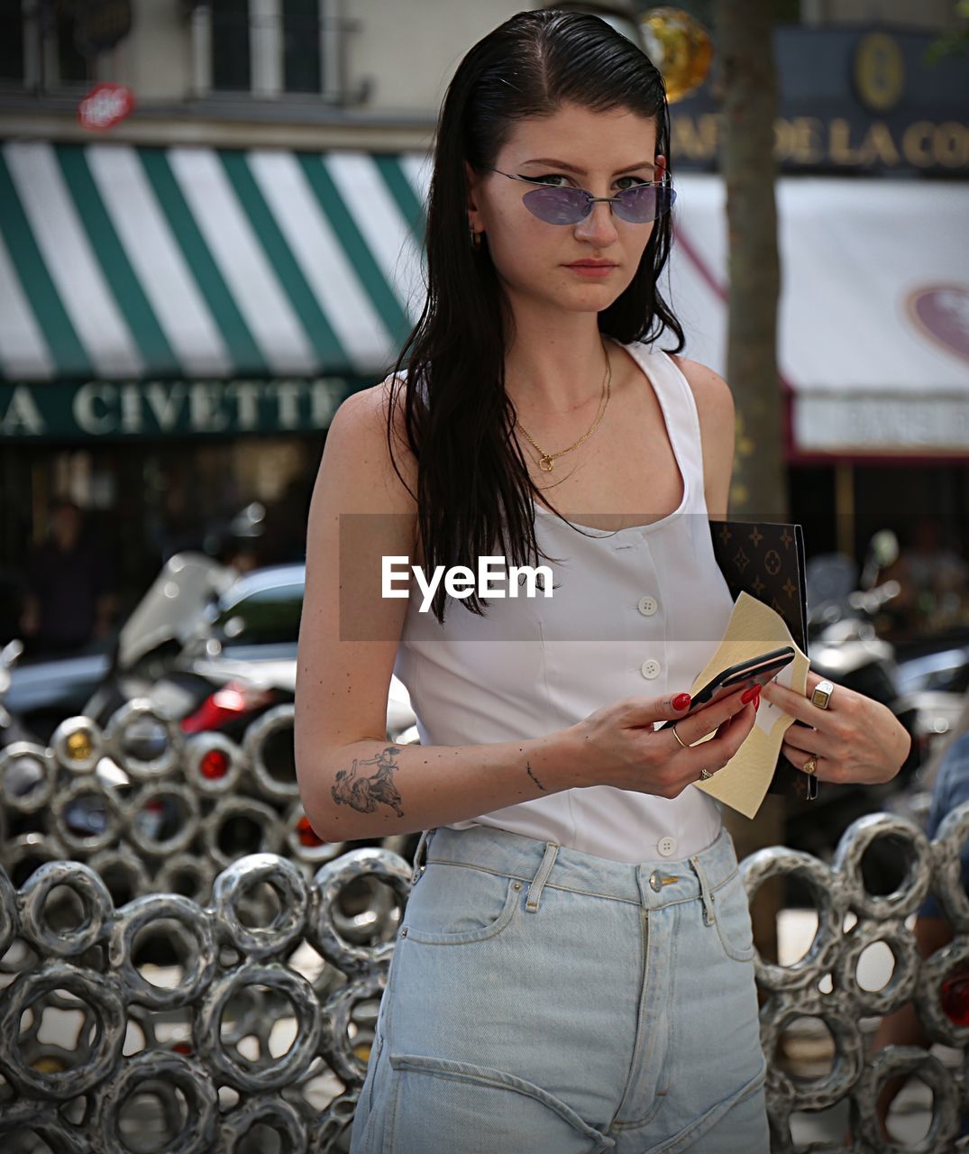 YOUNG WOMAN WITH EYEGLASSES STANDING IN BACKGROUND