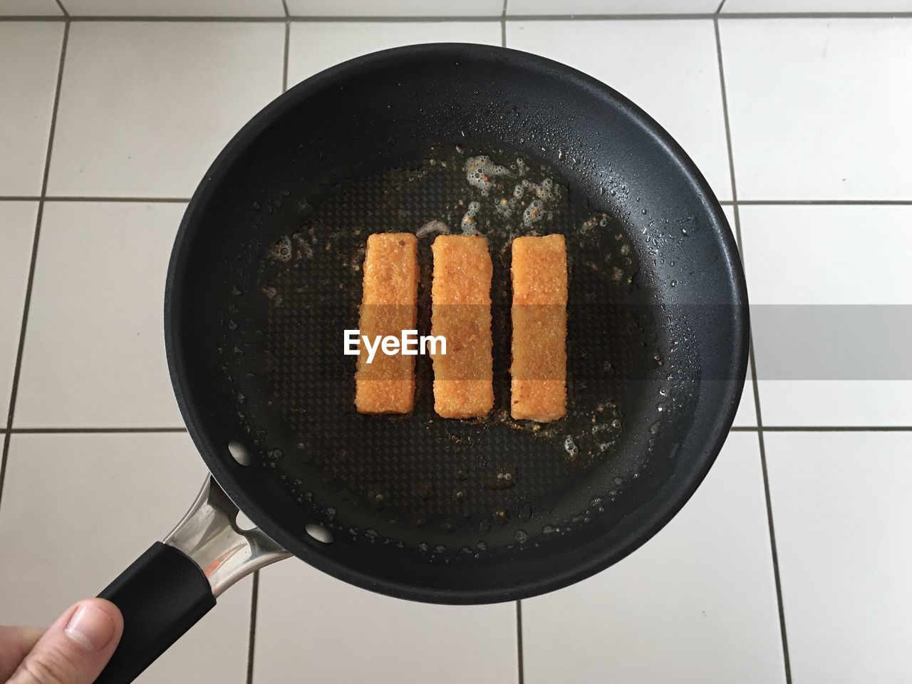 High angle view of person holding food in pan over floor