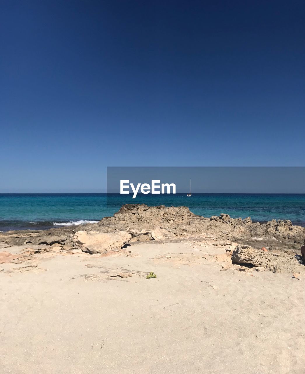 Scenic view of beach against clear blue sky