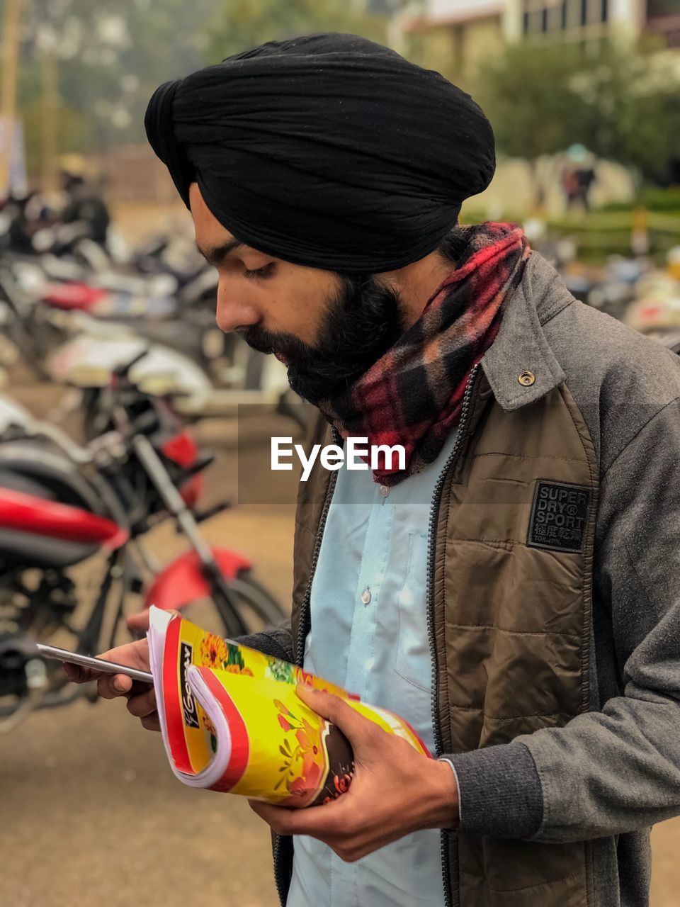 YOUNG MAN LOOKING AWAY WHILE STANDING ON OUTDOORS