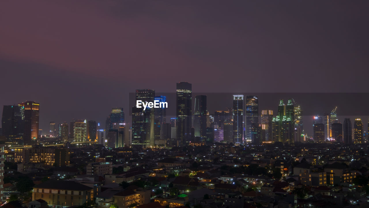 Illuminated buildings in city against sky at night