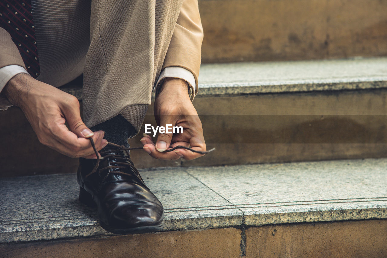 Low section of businessman tying shoelace on steps