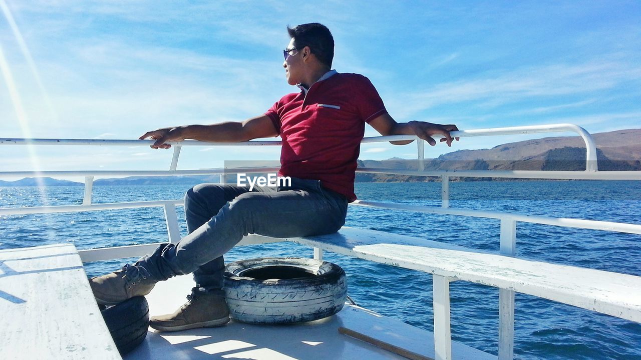 Young man sitting at boat sailing on sea