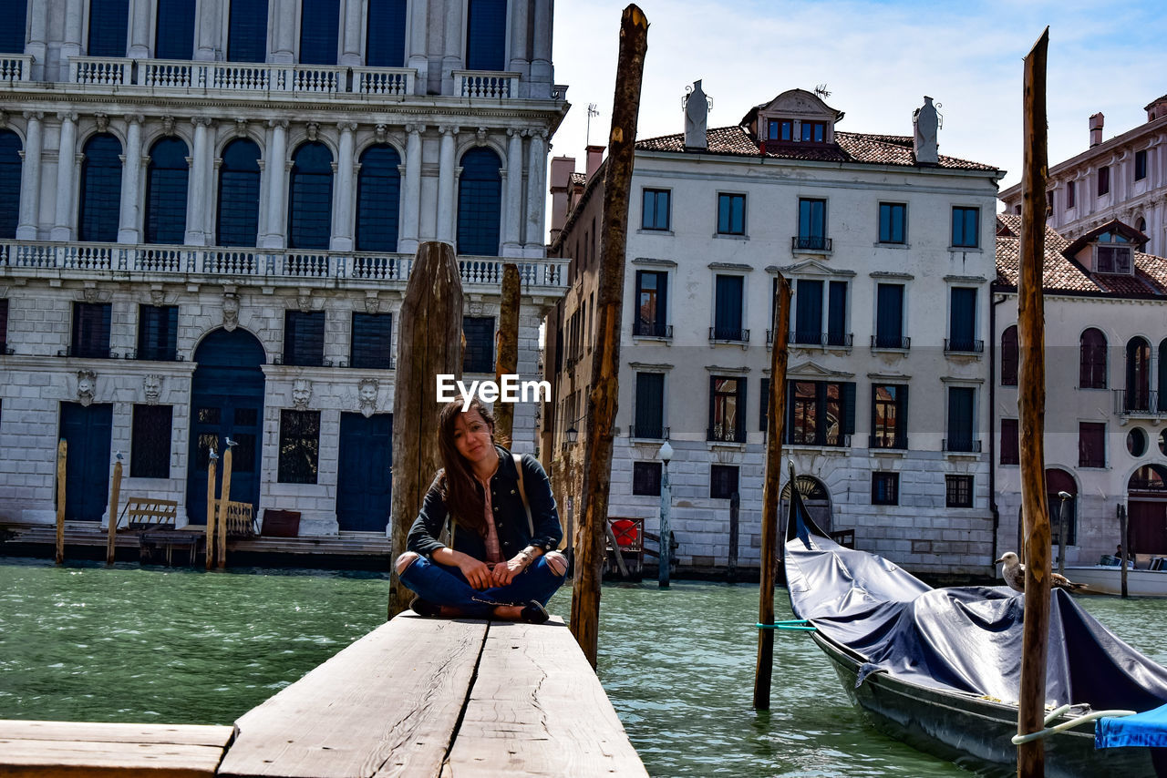 Full length of woman sitting on pier by lake