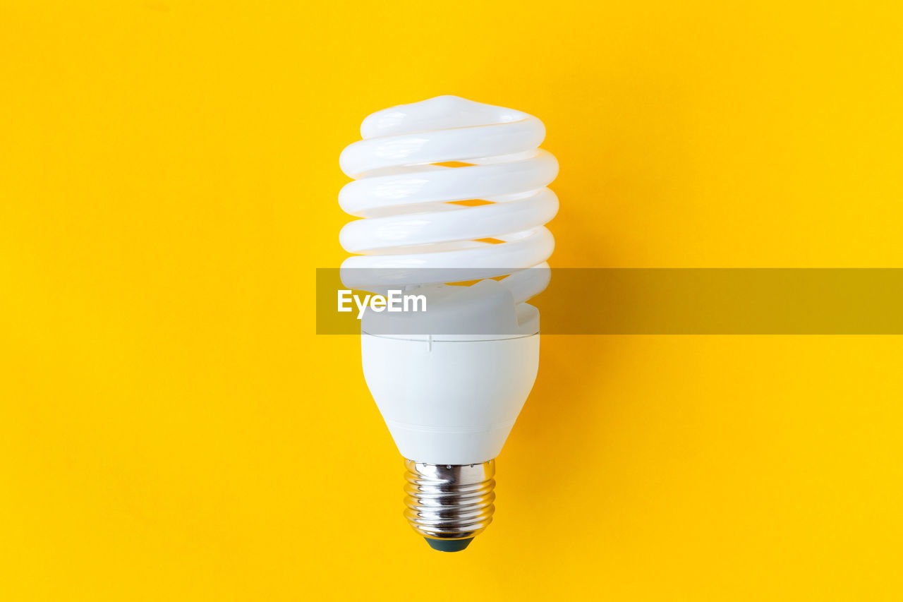 Close-up of light bulb against yellow background