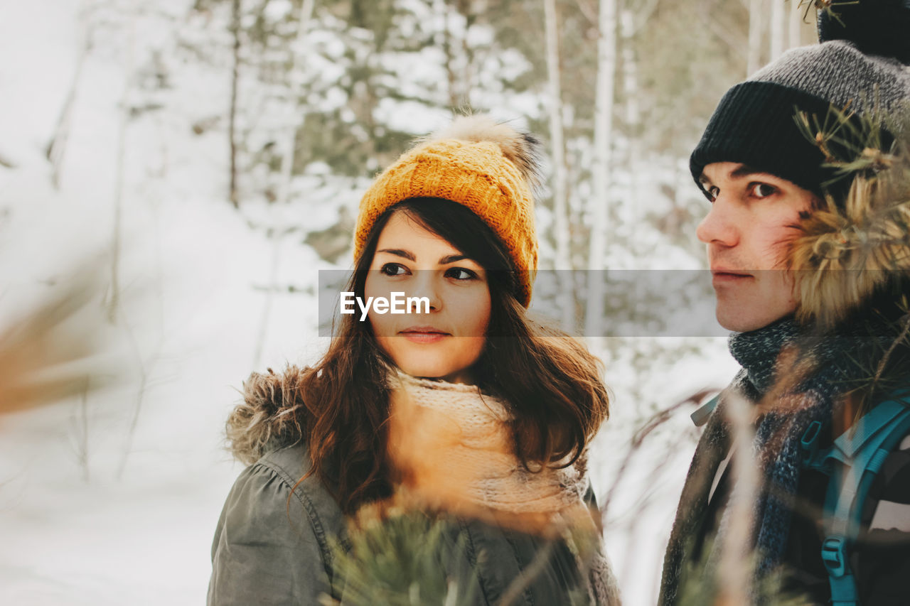 Couple looking away in forest during winter