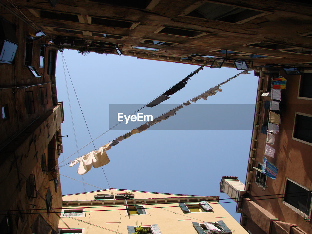 Low angle view of clothesline amidst buildings against sky