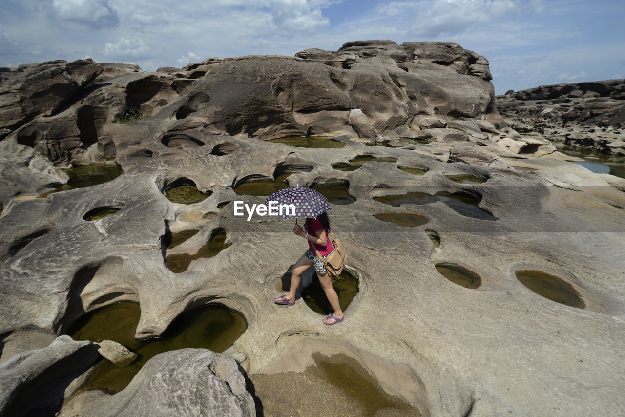 WOMAN STANDING ON ROCKS