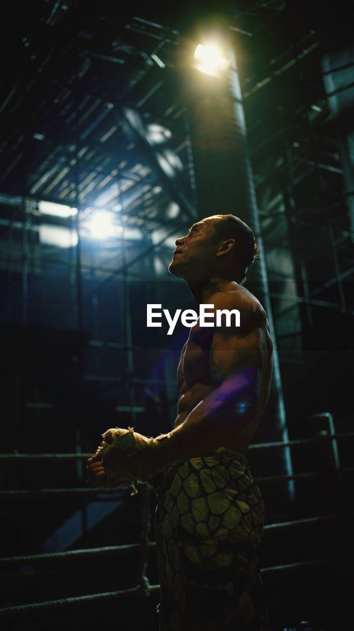 Side view of shirtless man standing in boxing ring