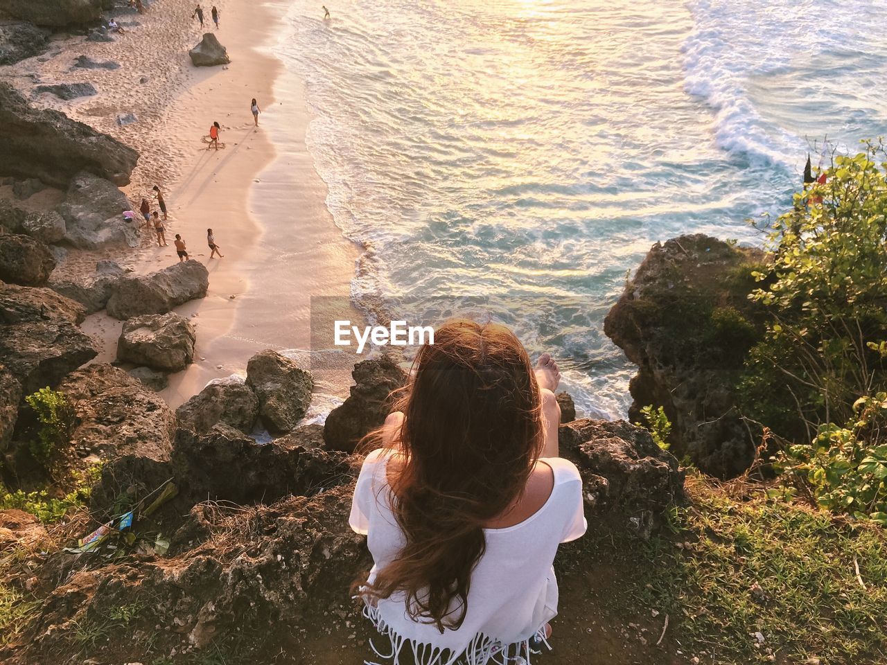 Rear view of woman sitting on rock against sea