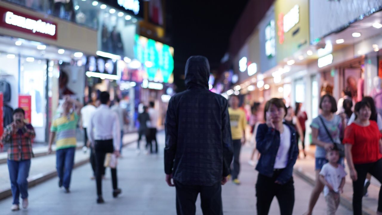 GROUP OF PEOPLE WALKING IN CITY AT NIGHT