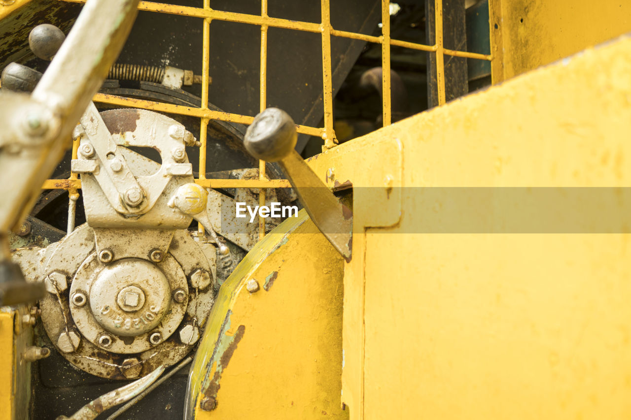 The old yellow digger was parked in a park. ,inside the loader gear