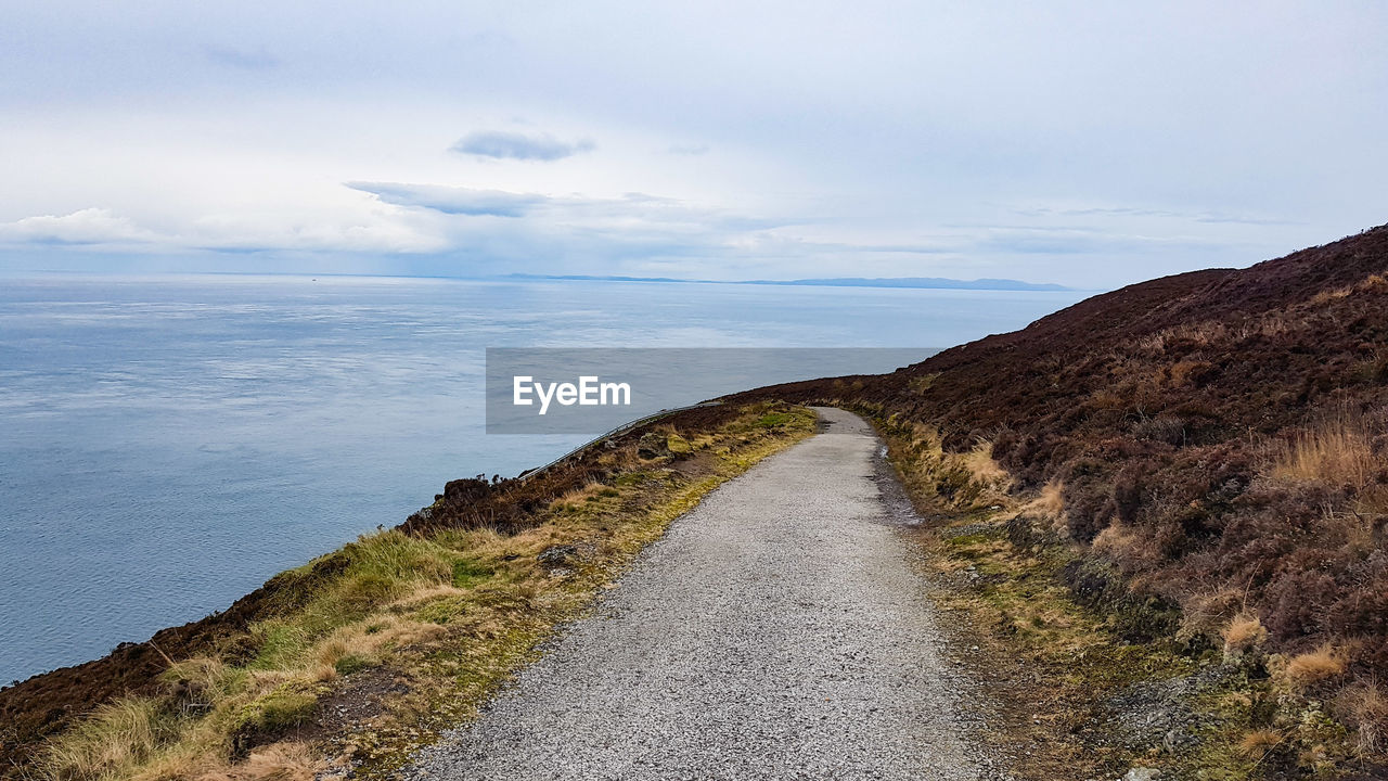 Scenic view of road by sea against sky