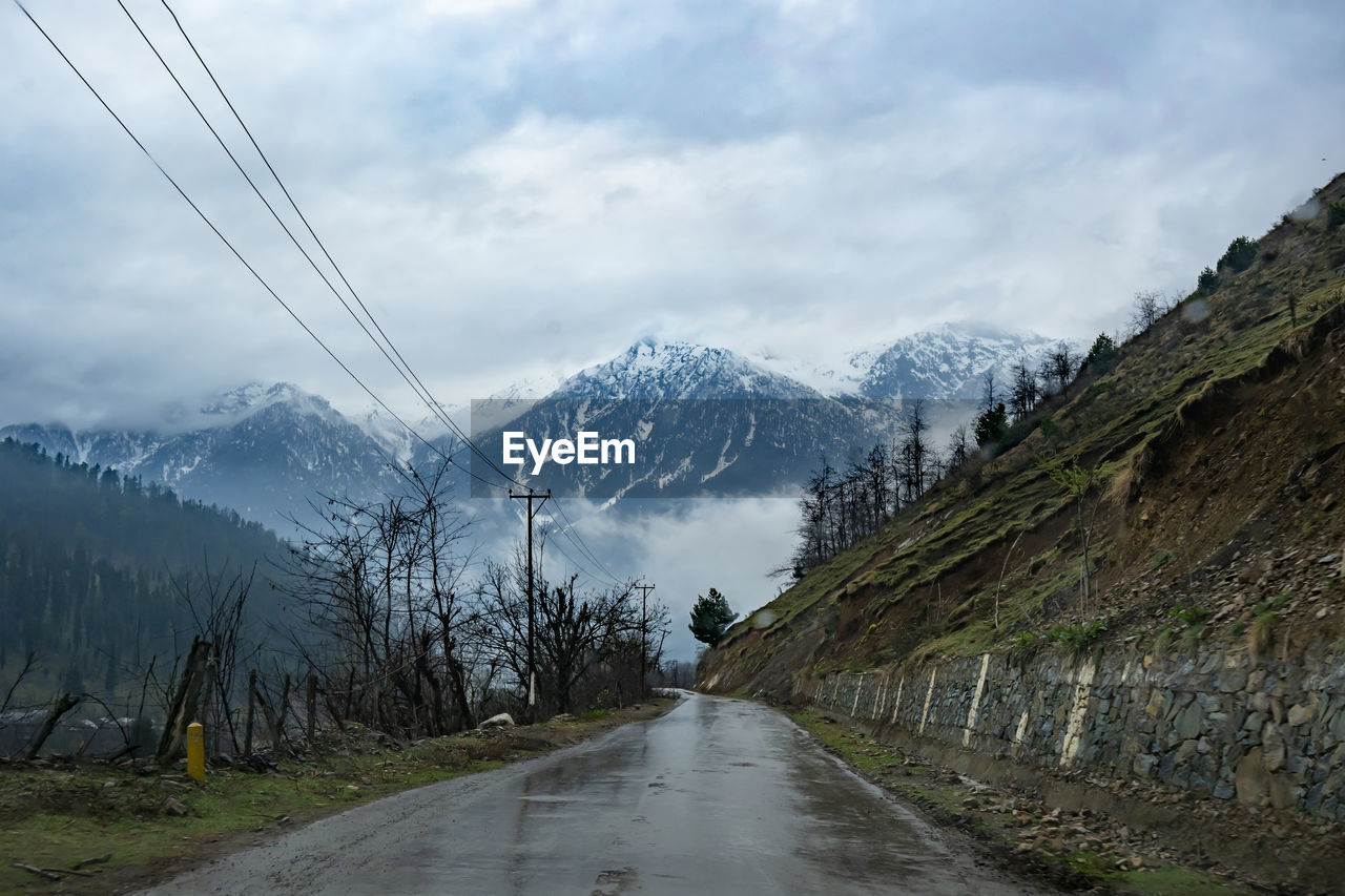 ROAD BY SNOWCAPPED MOUNTAIN AGAINST SKY