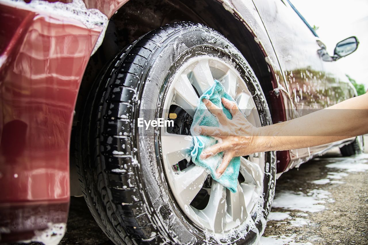 Cropped hands of man washing car tire