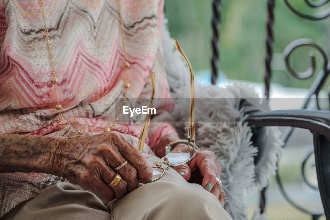 Midsection of senior woman cleaning eyeglasses