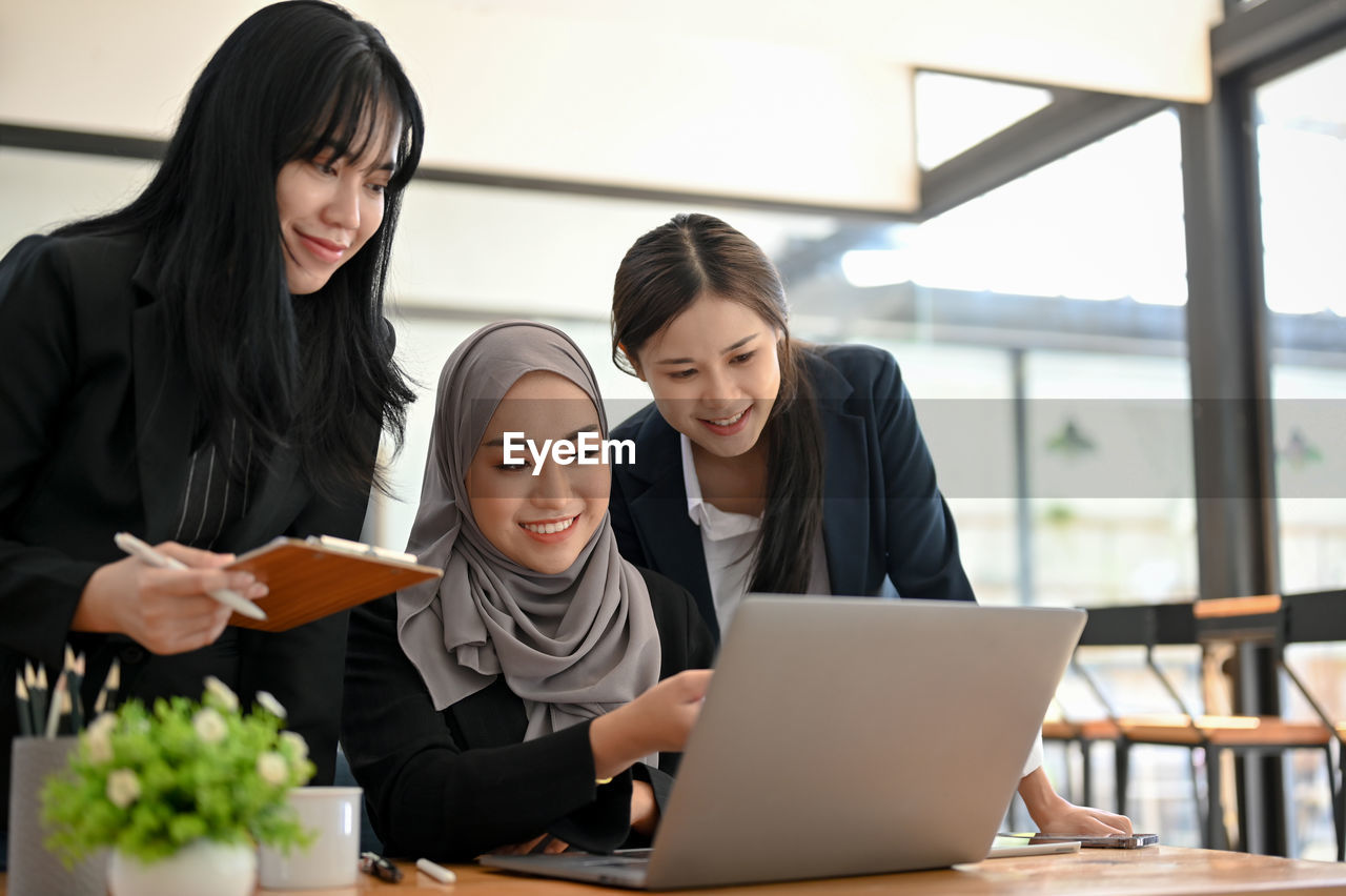 friends using laptop while sitting at office