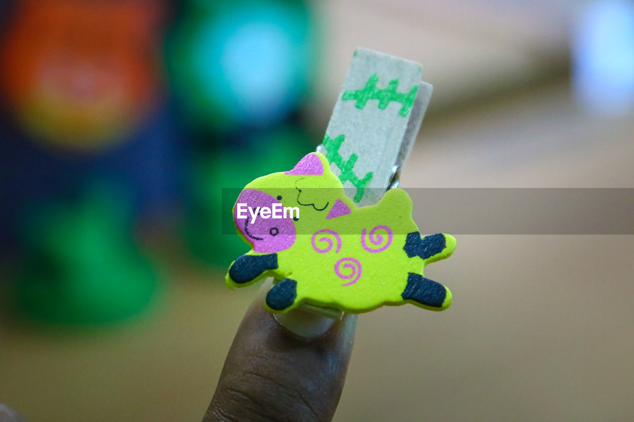 CLOSE-UP OF HAND HOLDING MULTI COLORED HUMAN EYE