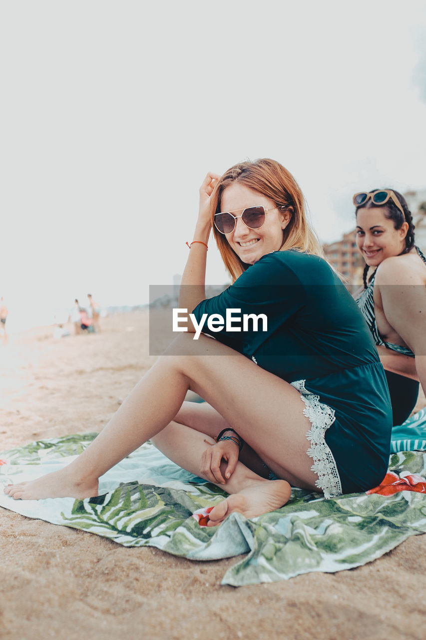 PORTRAIT OF BEAUTIFUL WOMAN SITTING ON BEACH