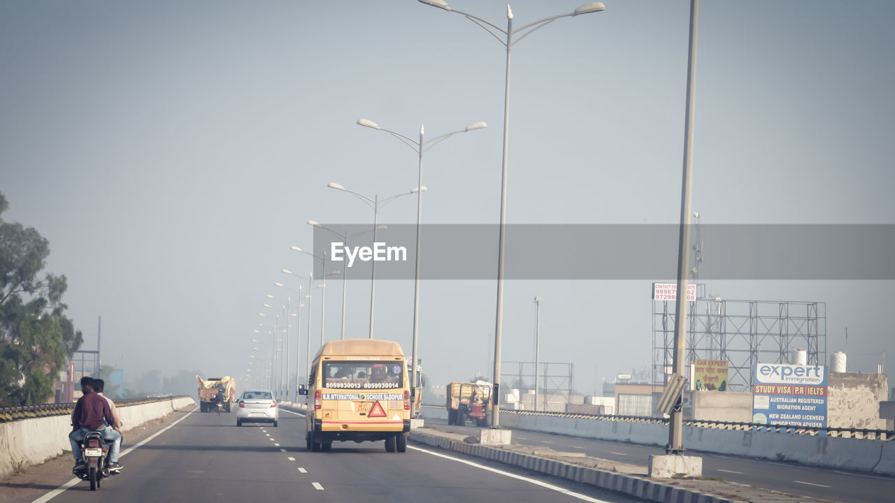 VEHICLES ON ROAD AGAINST CLEAR SKY