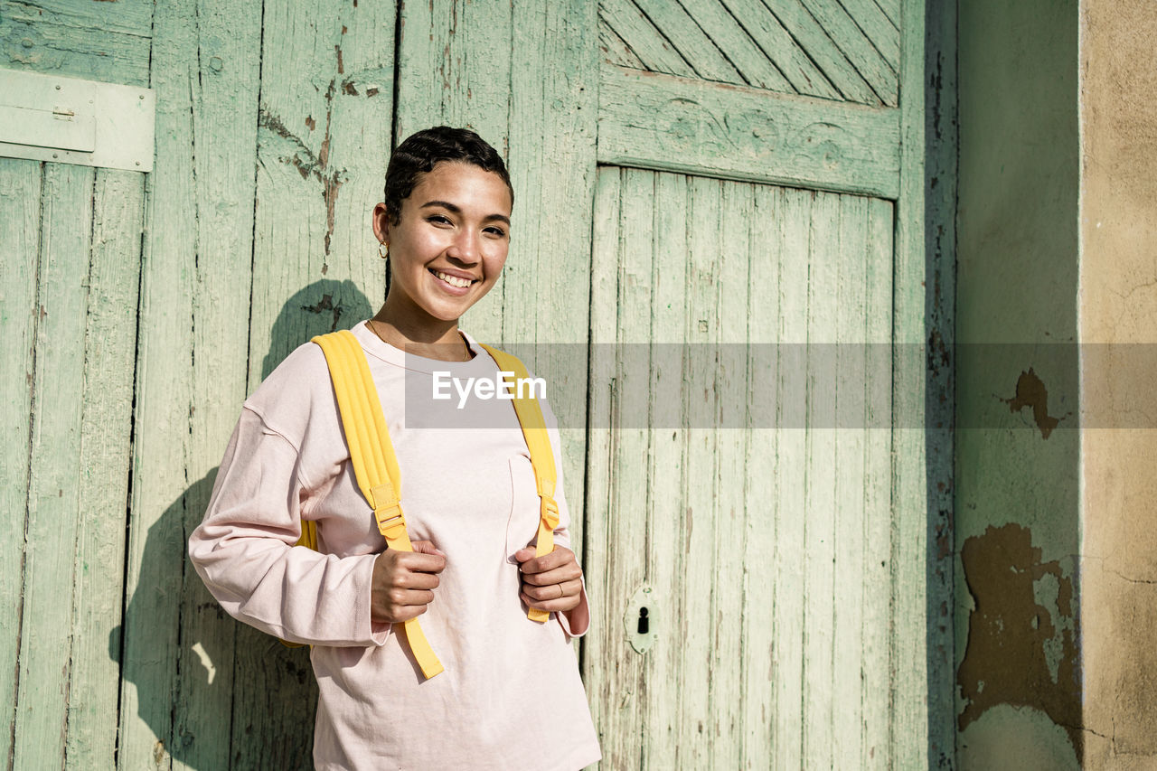 Smiling woman with short hair in front of old door
