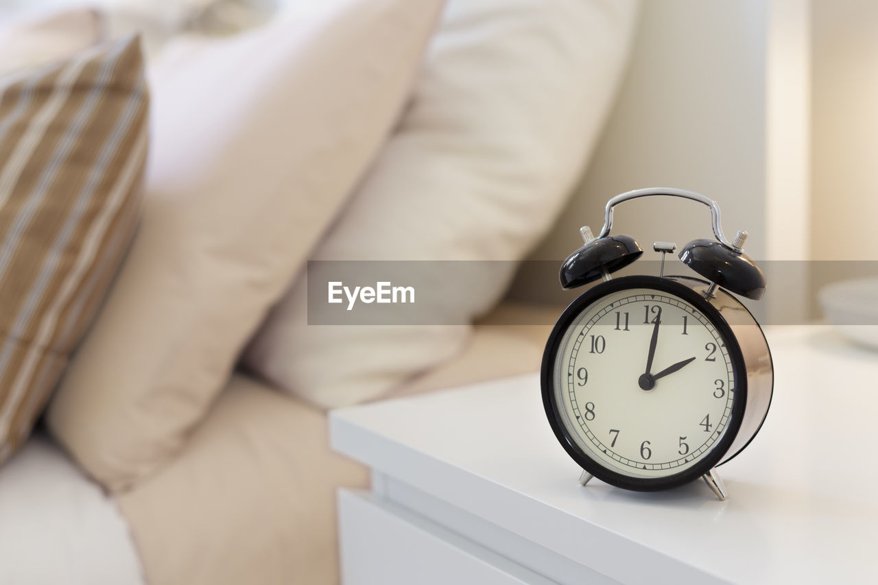 Close-up of clock on table by bed at home