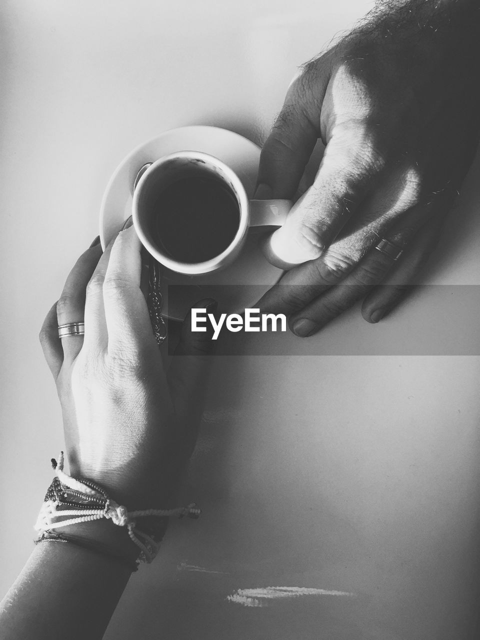 Cropped hands of couple holding coffee on table