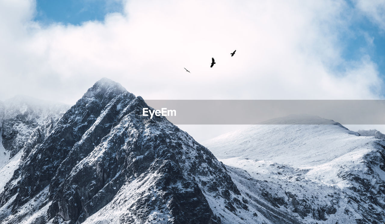 Majestic panoramic scenery of rough rocky slopes of pyrenees mountain range covered with snow under cloudy sky in el pas de la casa