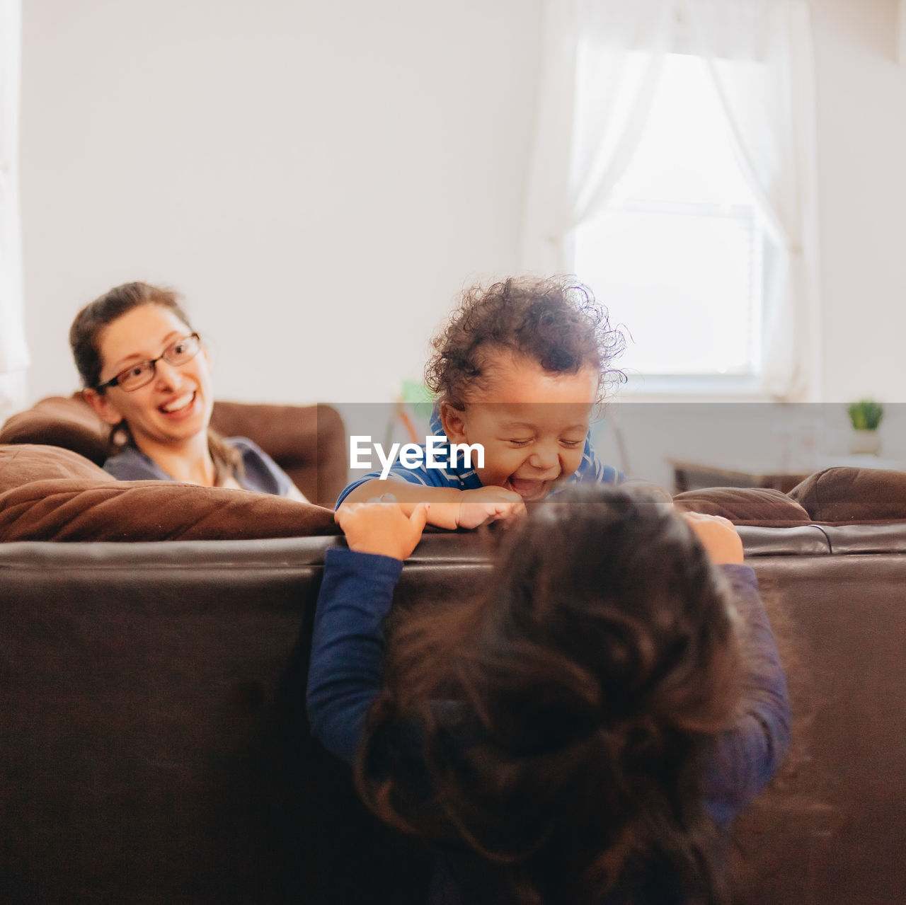 Siblings playing by mother at home