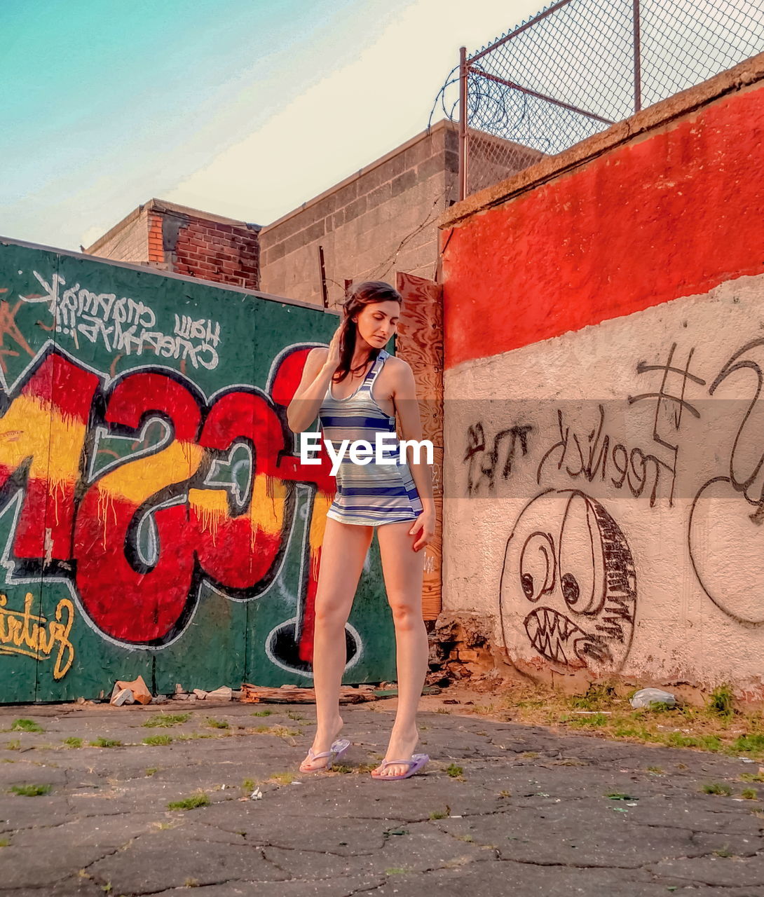 WOMAN STANDING BY GRAFFITI ON WALL