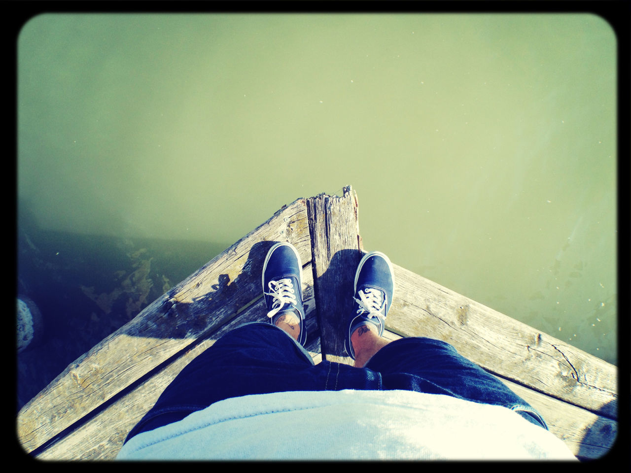 Low section of man standing on pier over lake