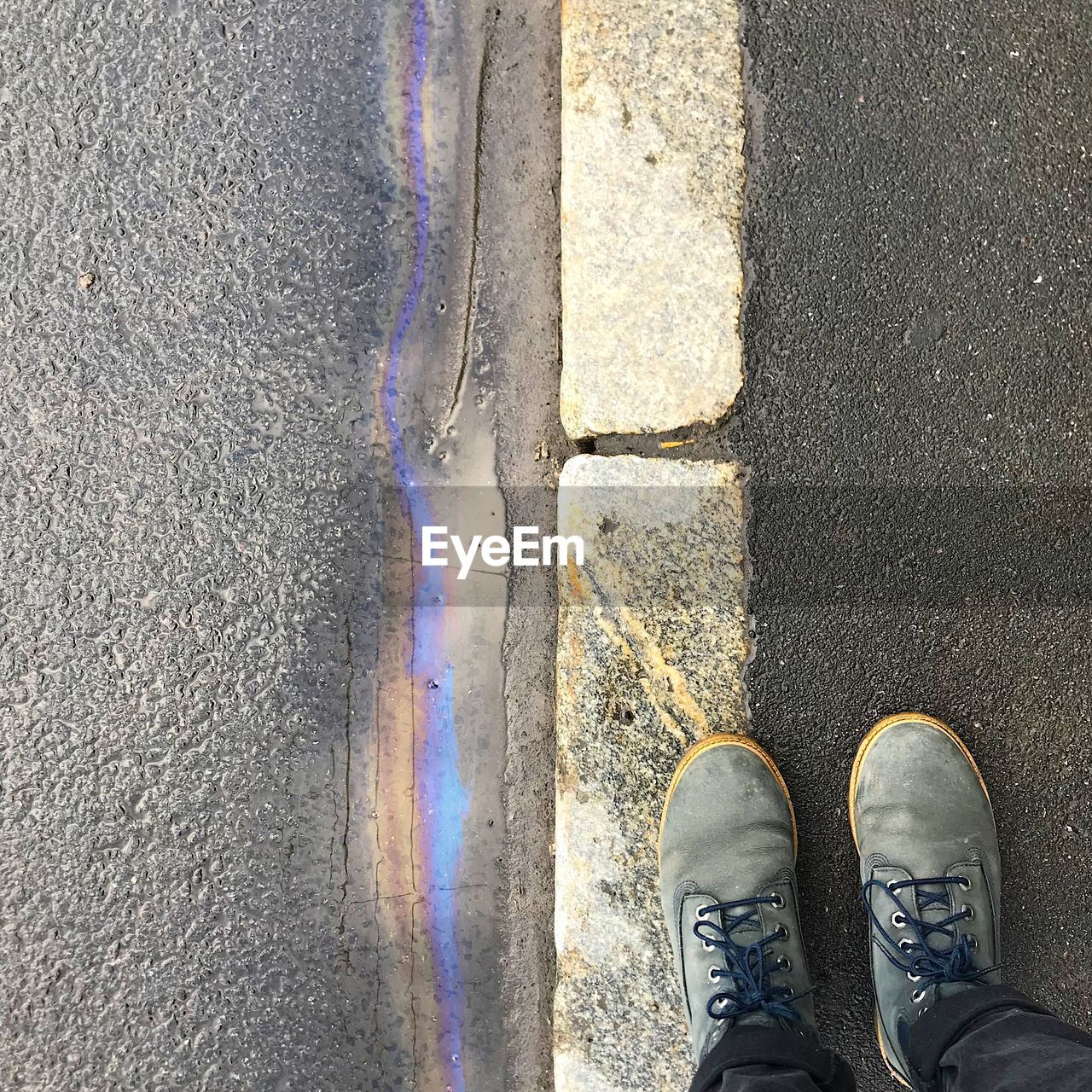 LOW SECTION OF PERSON STANDING ON ROAD BY STREET