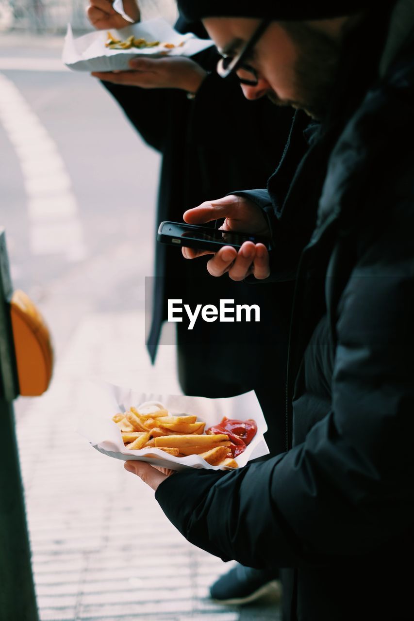 Man photographing pasta on footpath