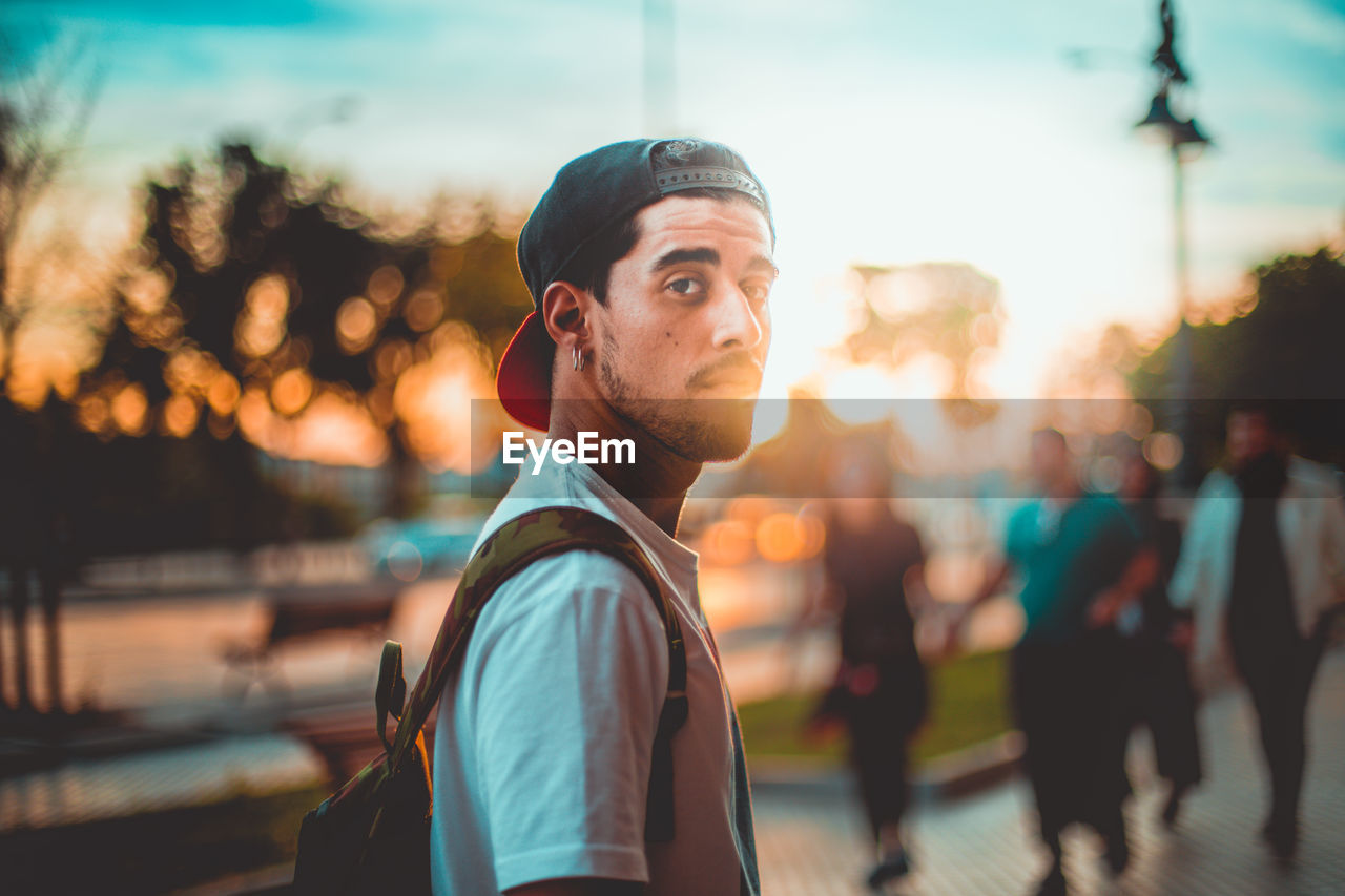 Portrait of young man in city against sky