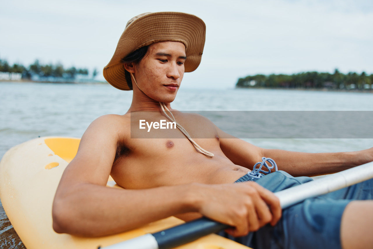 portrait of shirtless man swimming in boat