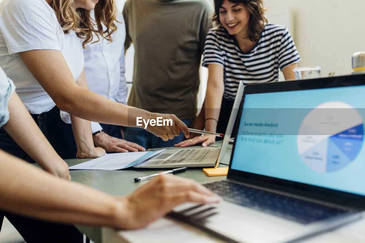 Businesswoman explaining colleagues on laptop in meeting at work place