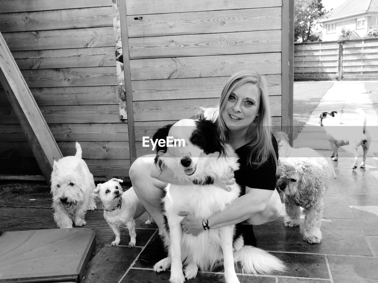 Portrait of woman with dogs against fence