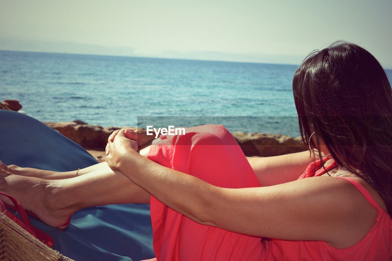 Side view of woman at beach against sky