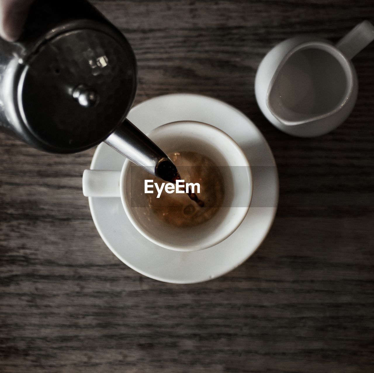 Directly above shot of jug pouring coffee in cup on table