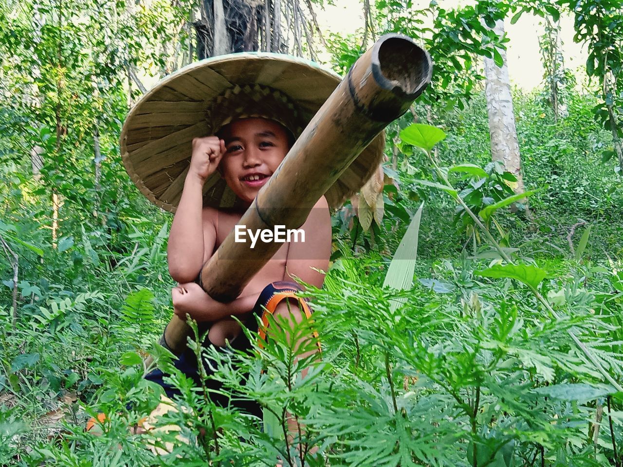 Portrait of shirtless boy holding stick at forest