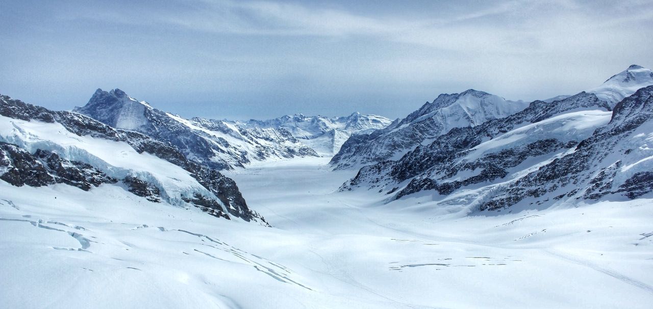 Scenic view of snowcapped mountains against cloudy sky