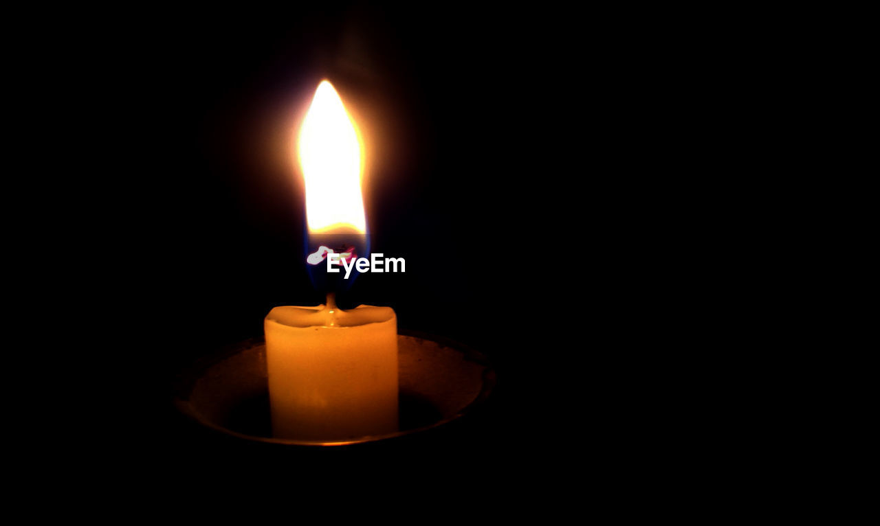 Close-up of lit  candle in dark room