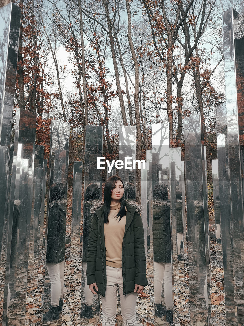 PORTRAIT OF YOUNG WOMAN STANDING BY BARE TREES IN WINTER