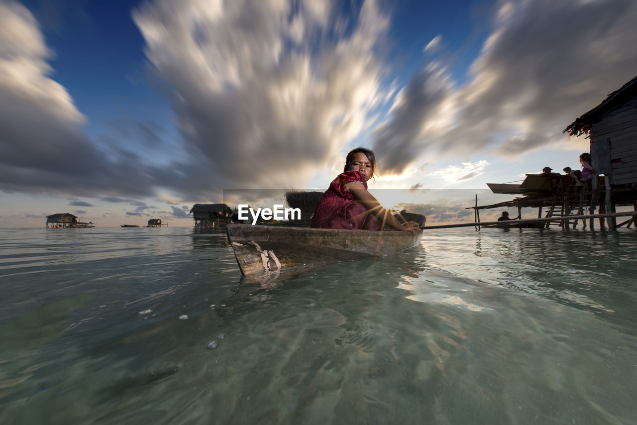 YOUNG WOMAN SWIMMING IN SEA AGAINST SKY