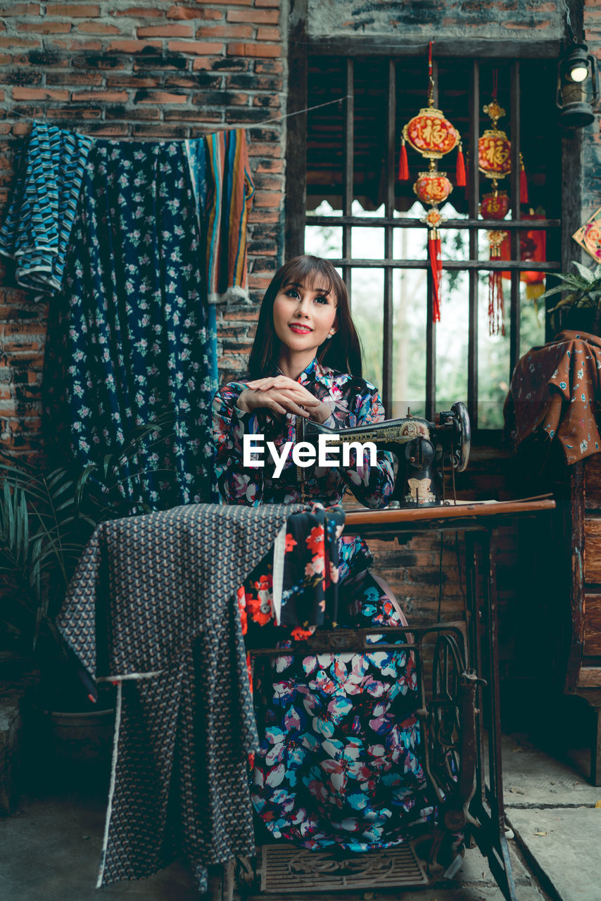 Woman sitting at sewing machine in home