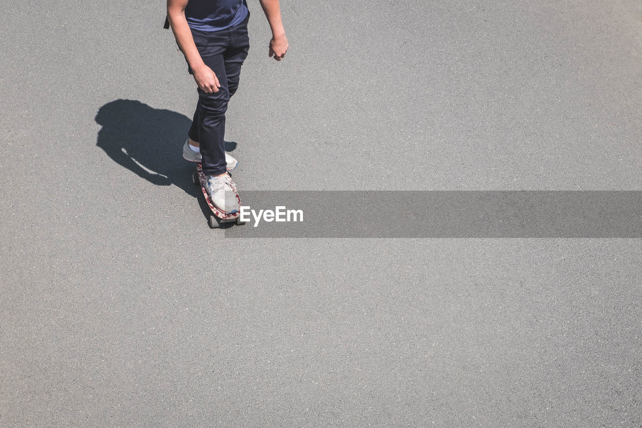 Low section of man skateboarding on road