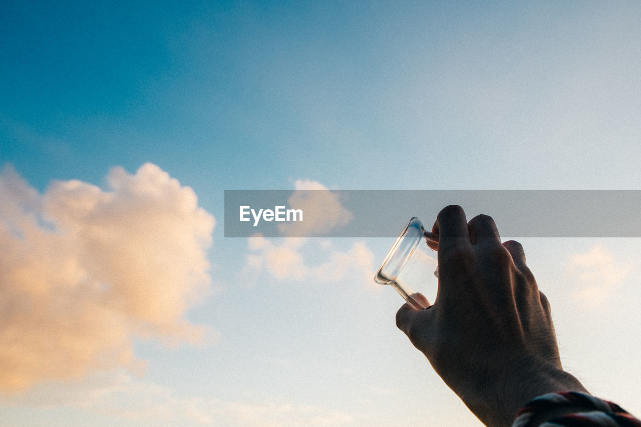 Low angle view of man with glass against sky