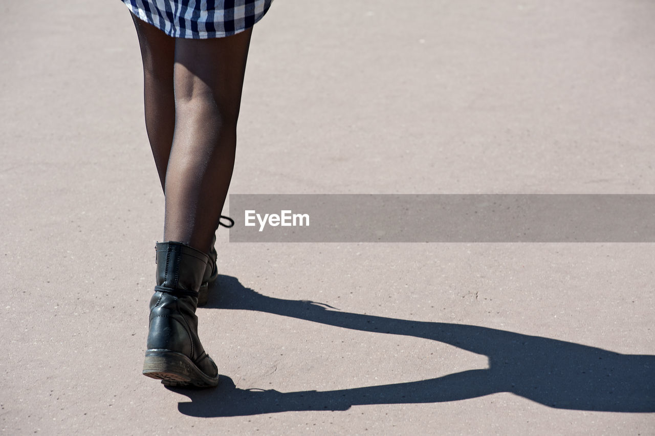 Low section of woman walking on road